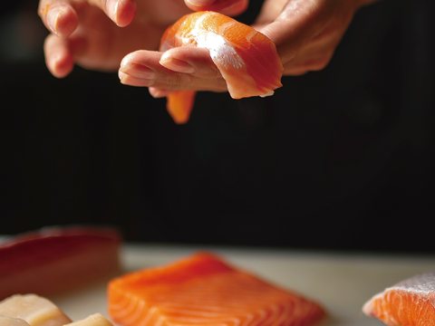 Salmon portion with nigiri being formed by hand
